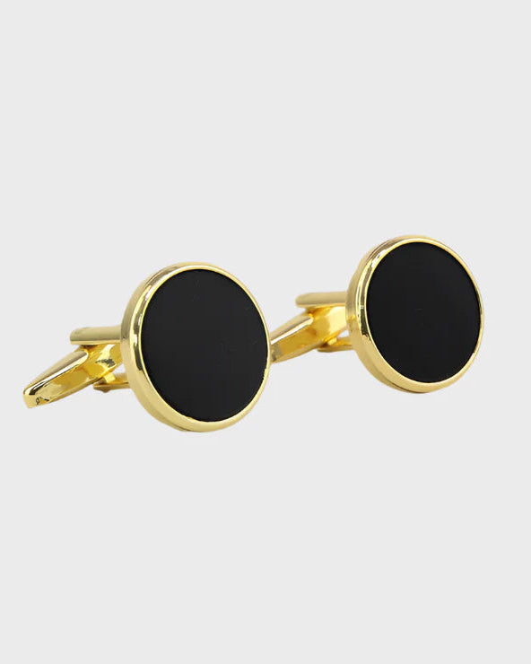 Gold cufflinks with black round stones on a light gray background
