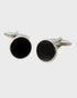 Pair of black round cufflinks with silver borders on a white background