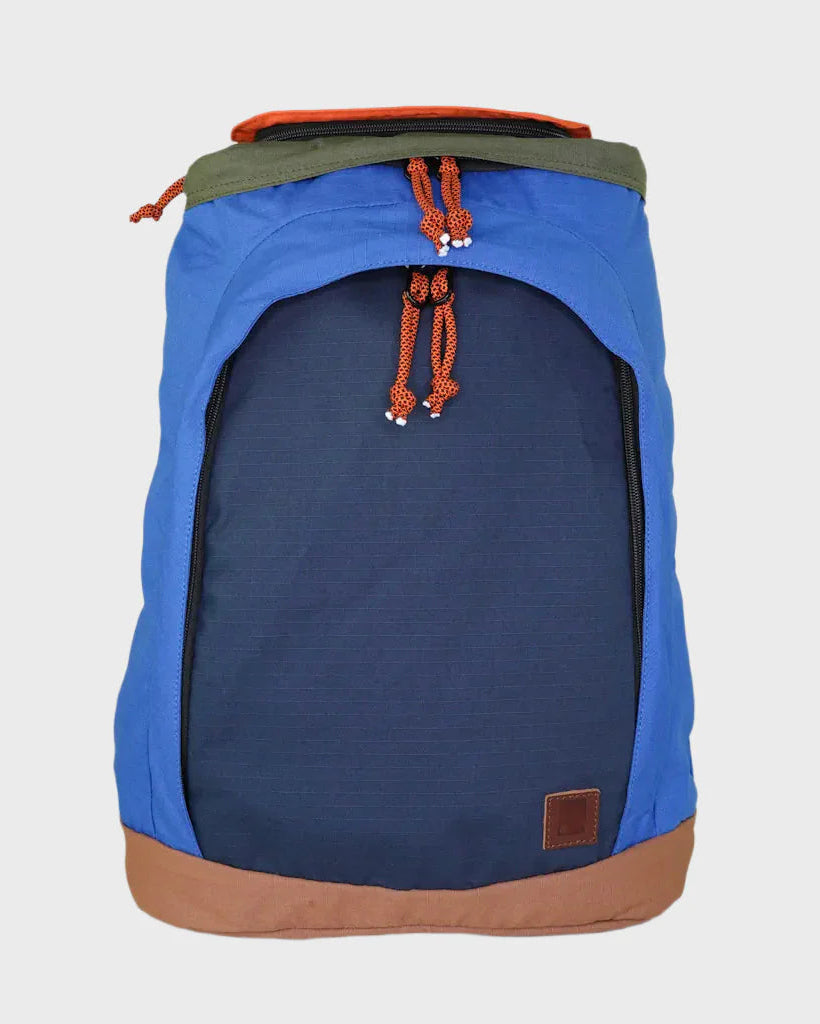A blue and navy backpack with orange drawstring cords, a brown base trim, and an olive green top flap, shown against a light gray background.