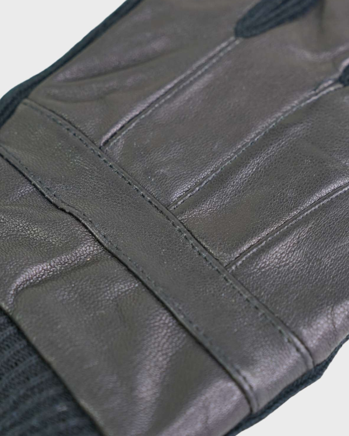 Close-up of a black leather glove with visible stitching on a light gray background