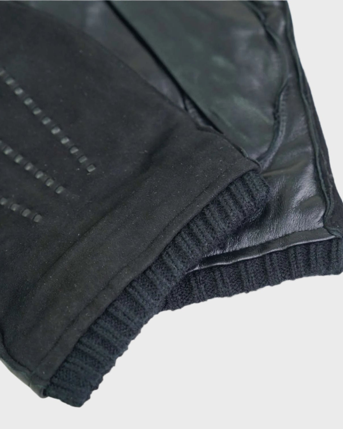 Close-up of a black leather gloves on a light gray background