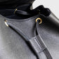 Close-up of a black leather bag with drawstring and visible brand logo.