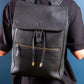 Person wearing a black leather backpack against a blue background