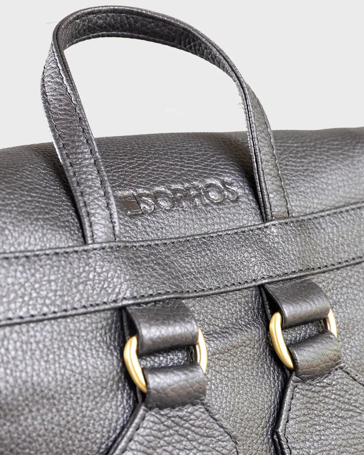 Close-up of a black leather backpack with visible brand name on a light gray background