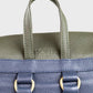 Close-up of a two-tone leather bag with green top section and navy bottom section.
