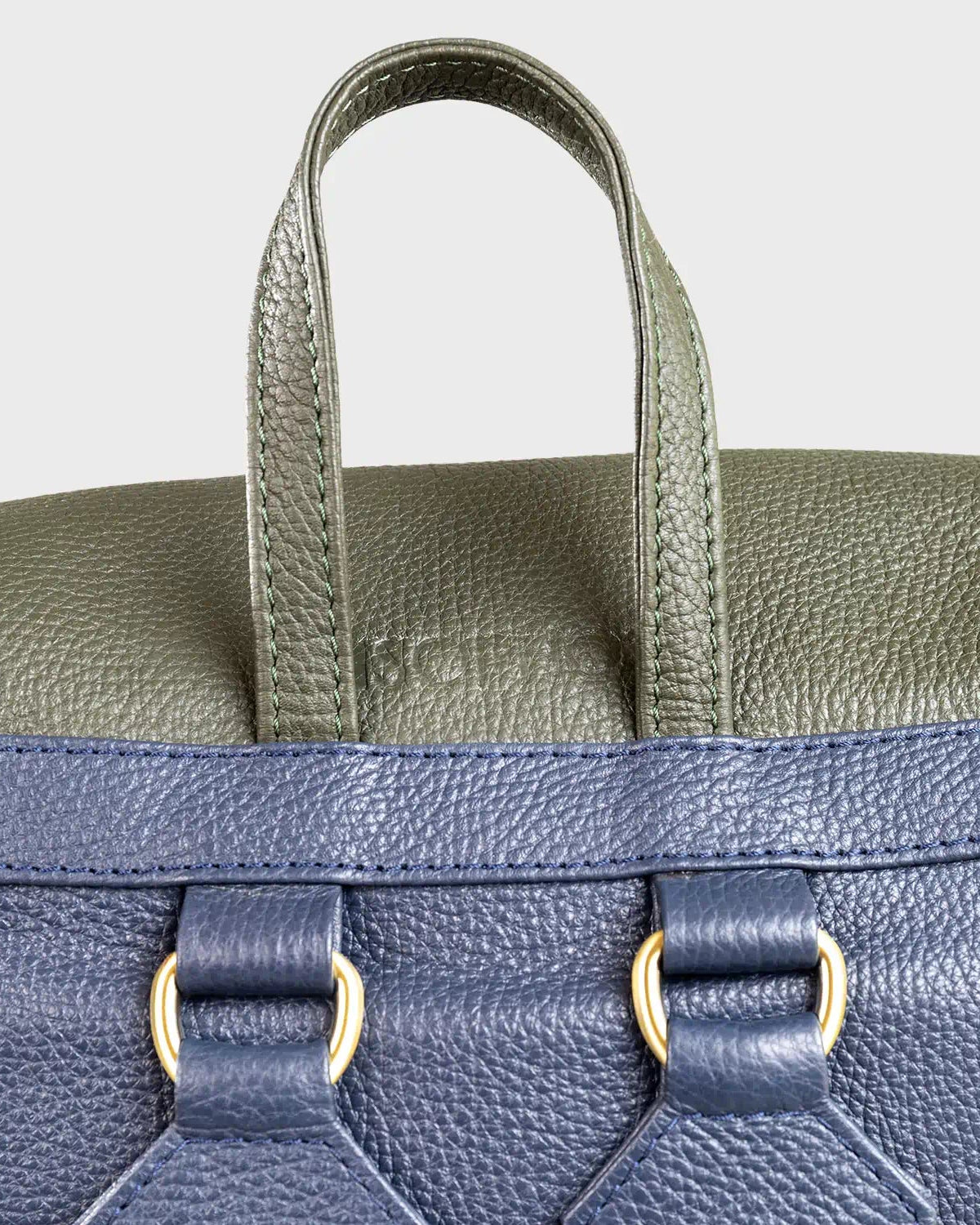 Close-up of a two-tone leather bag with green top section and navy bottom section.