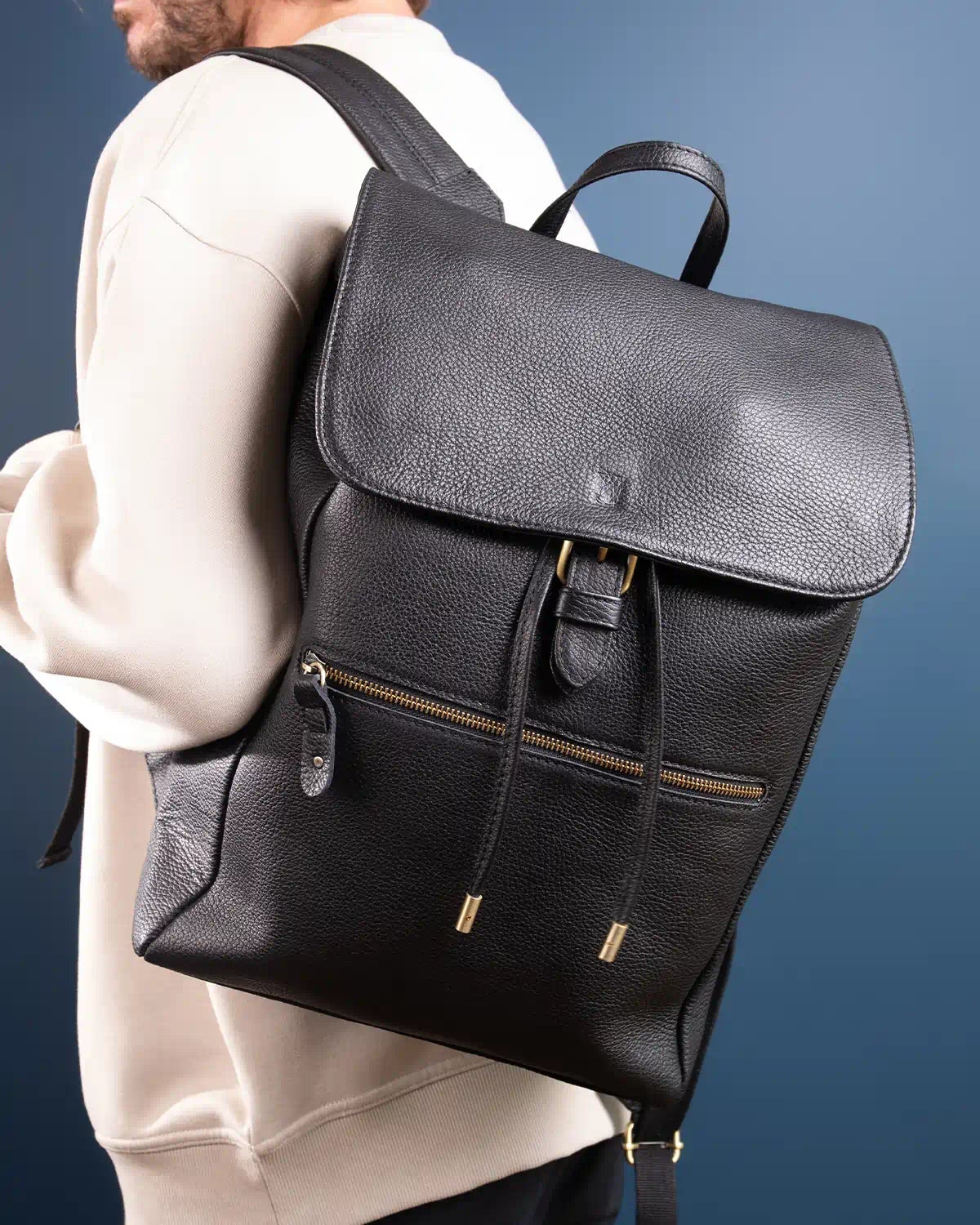 Person wearing a black leather backpack against a blue background