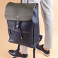 Person holding a navy blue backpack with a beige background