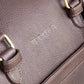 Close-up of a brown leather bag with gold buckles and branding.