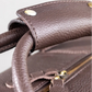 Close-up of a brown leather holdall with gold zipper and hardware.