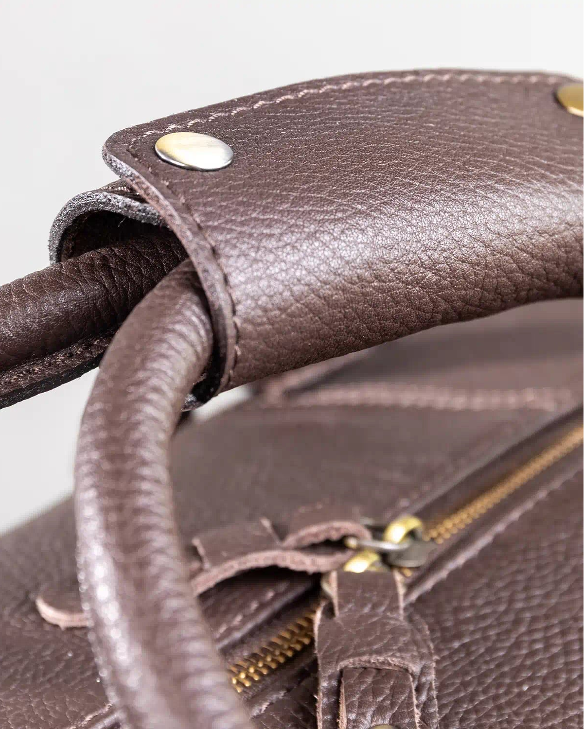 Close-up of a brown leather holdall with gold zipper and hardware.