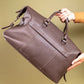 Brown leather holdall held by a person against a beige background