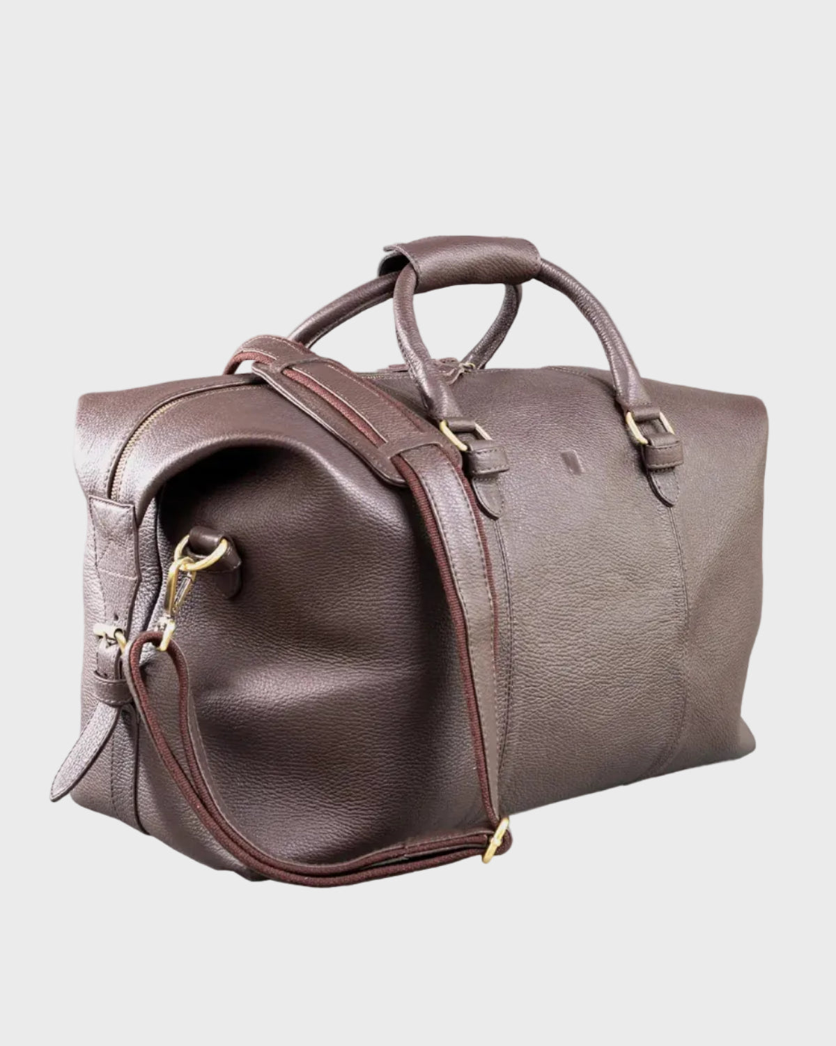 Brown leather holdall with gold hardware on a light gray background