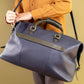 Person holding a navy holdall against a beige background