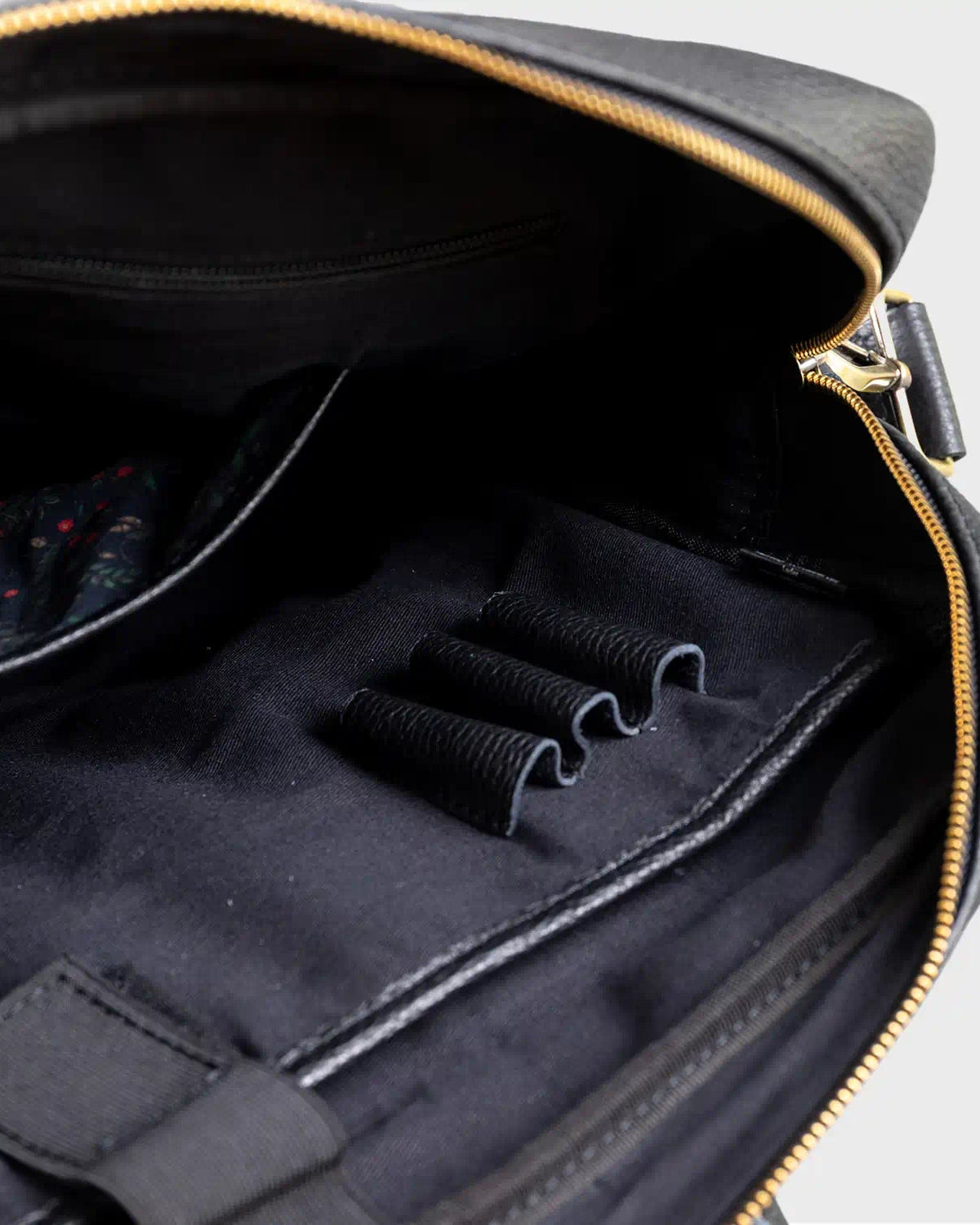 Close-up of a black bag with a zipper on a light gray background