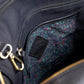 Close-up of a black bag with a floral patterned pocket.