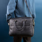 Person wearing a black leather shoulder bag against a blue background