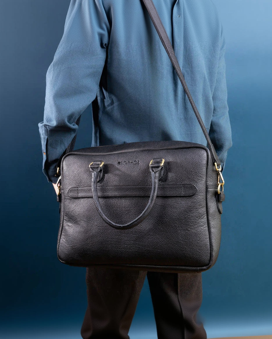 Person wearing a black leather shoulder bag against a blue background