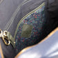 Close-up of a gray bag with a floral patterned patch and gold zipper.