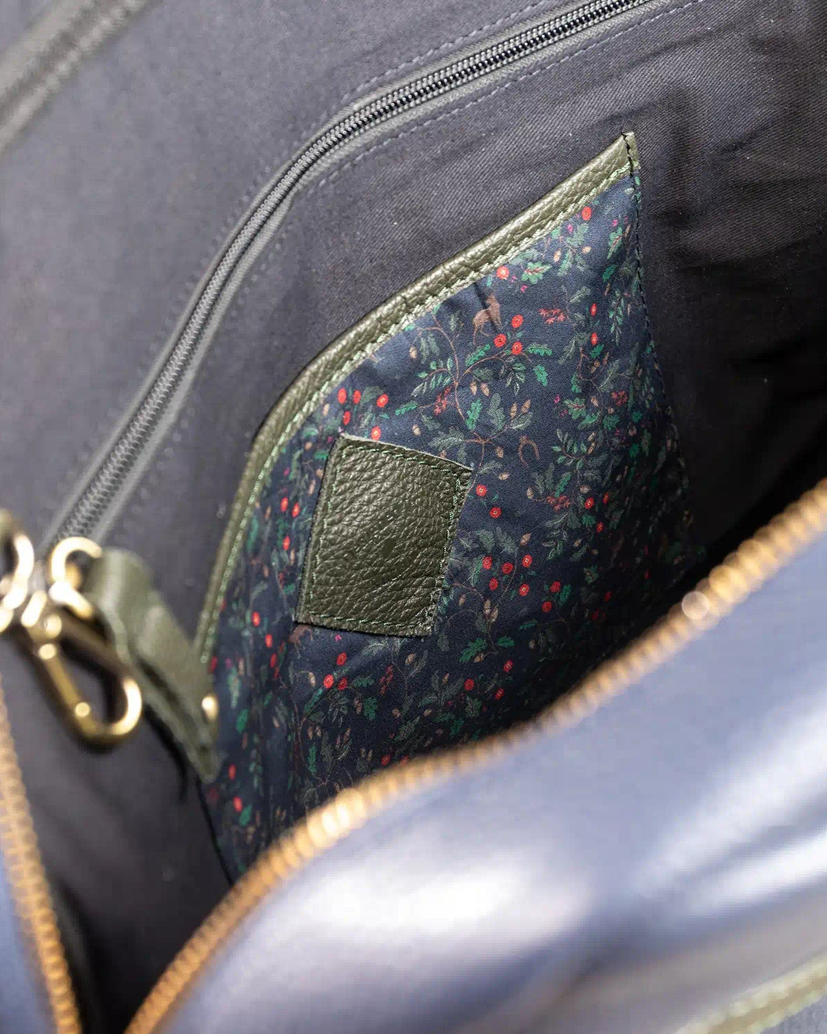 Close-up of a gray bag with a floral patterned patch and gold zipper.