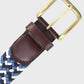 Braided belt with brown leather strap and brass buckle on a light gray background
