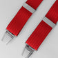 Red braces with silver clips on a light gray background