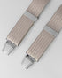 Beige braces with silver clips on a light gray background