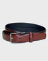 Tan leather belt with silver buckle on a light gray background