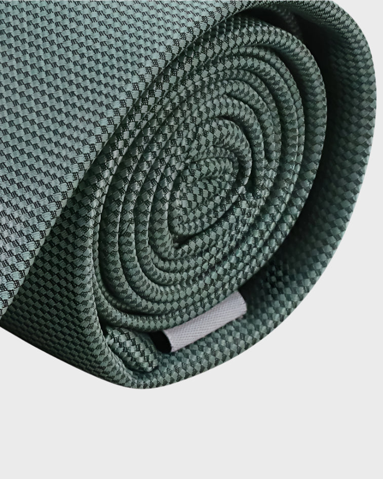 Rolled-up green tie on a light gray background