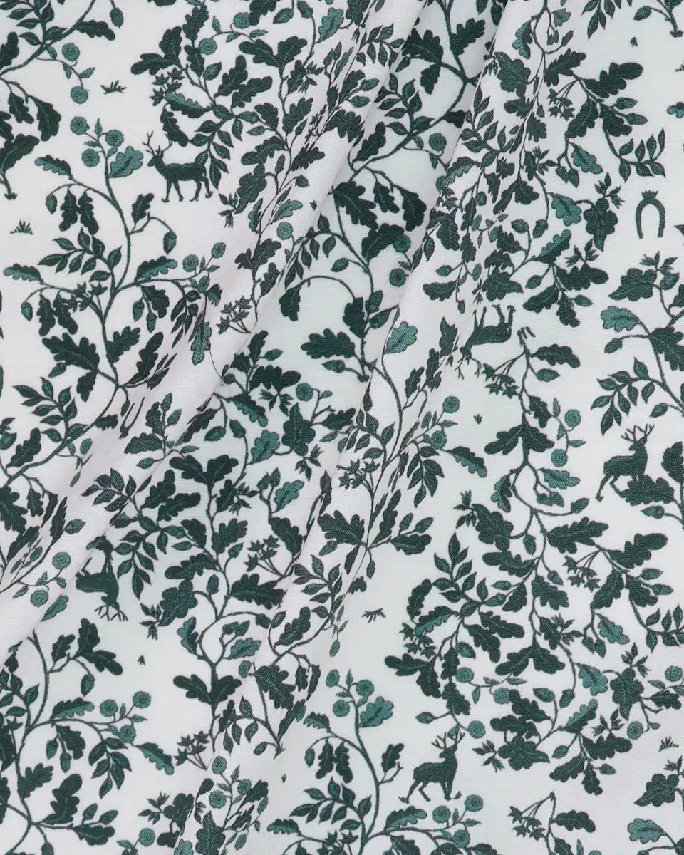 Patterned fabric with green leaves and deer on a white background