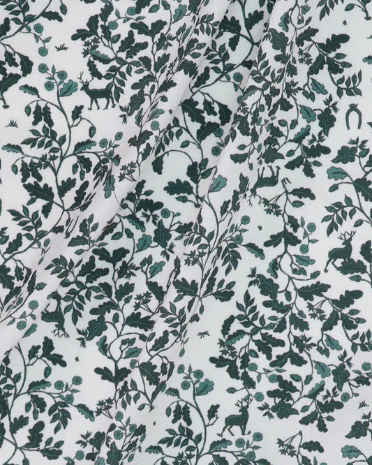 Patterned fabric with green leaves and deer on a white background