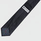 Black tie with a visible brand label on a light gray background
