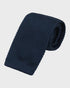 Navy blue knitted tie on a light gray background