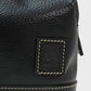 Close-up of a black leather bag with stitching detail on a white background