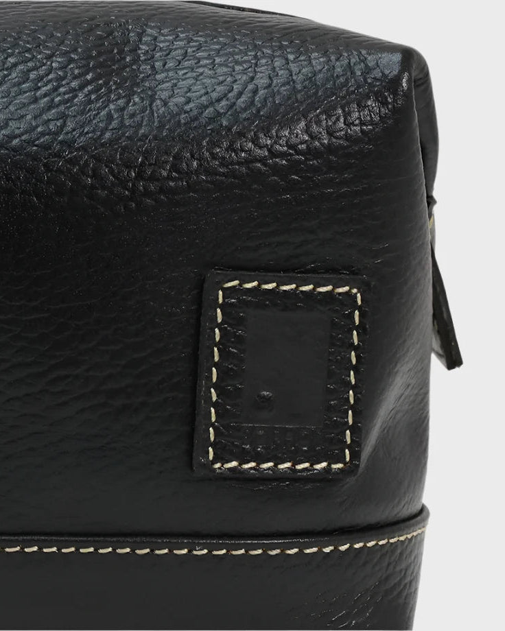 Close-up of a black leather bag with stitching detail on a white background