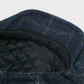 Blue checkered flat cap with black quilted interior on a light gray background
