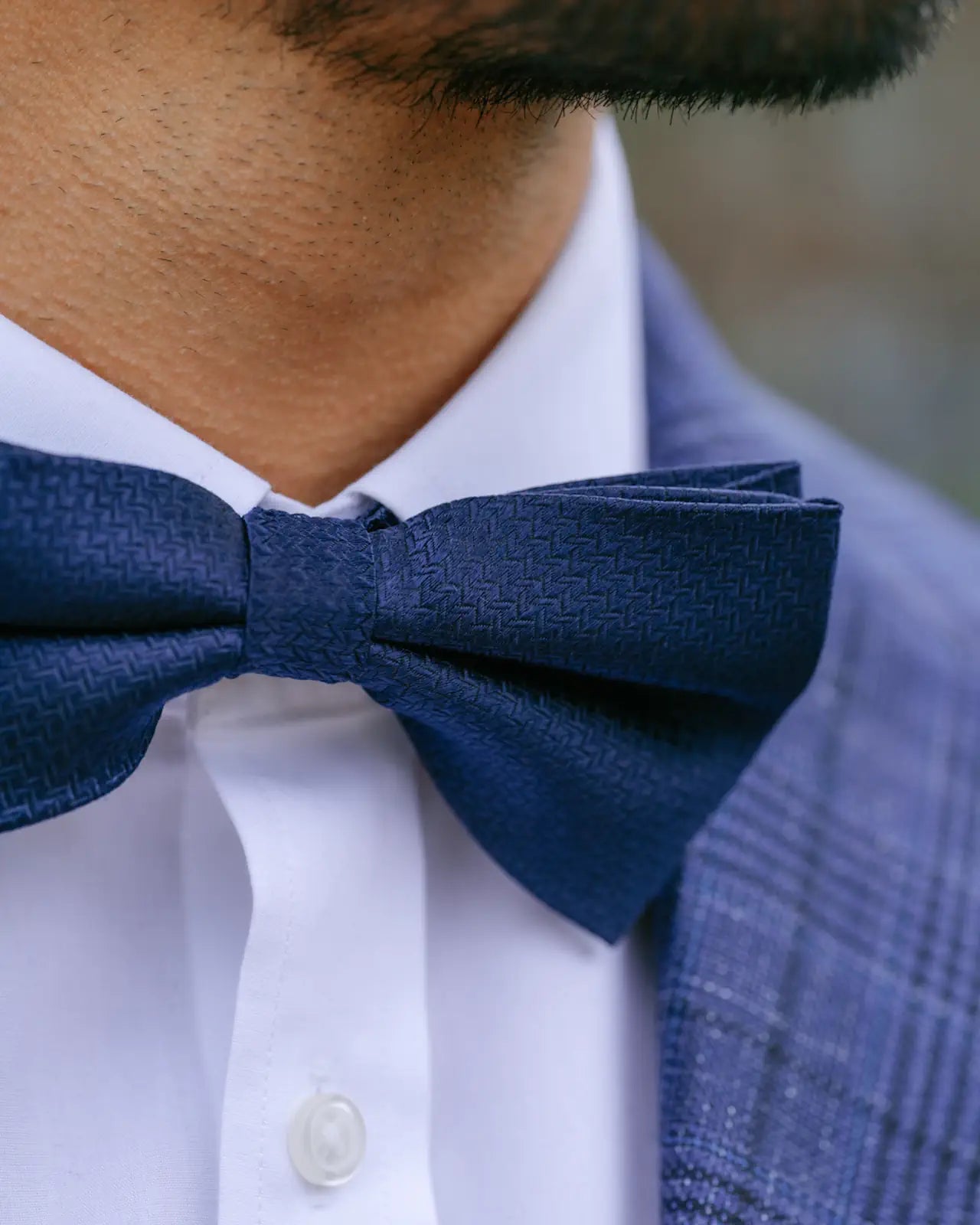 Navy blue bow tie worn by a person with a blurred background