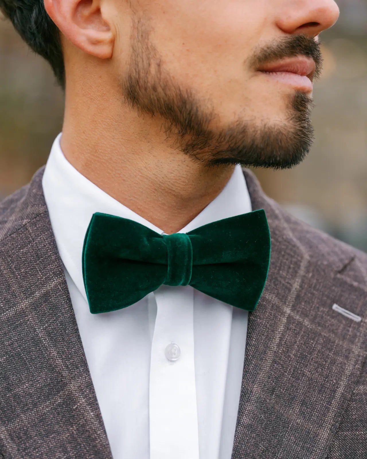 Man wearing a green velvet bow tie with a brown suit and white shirt.