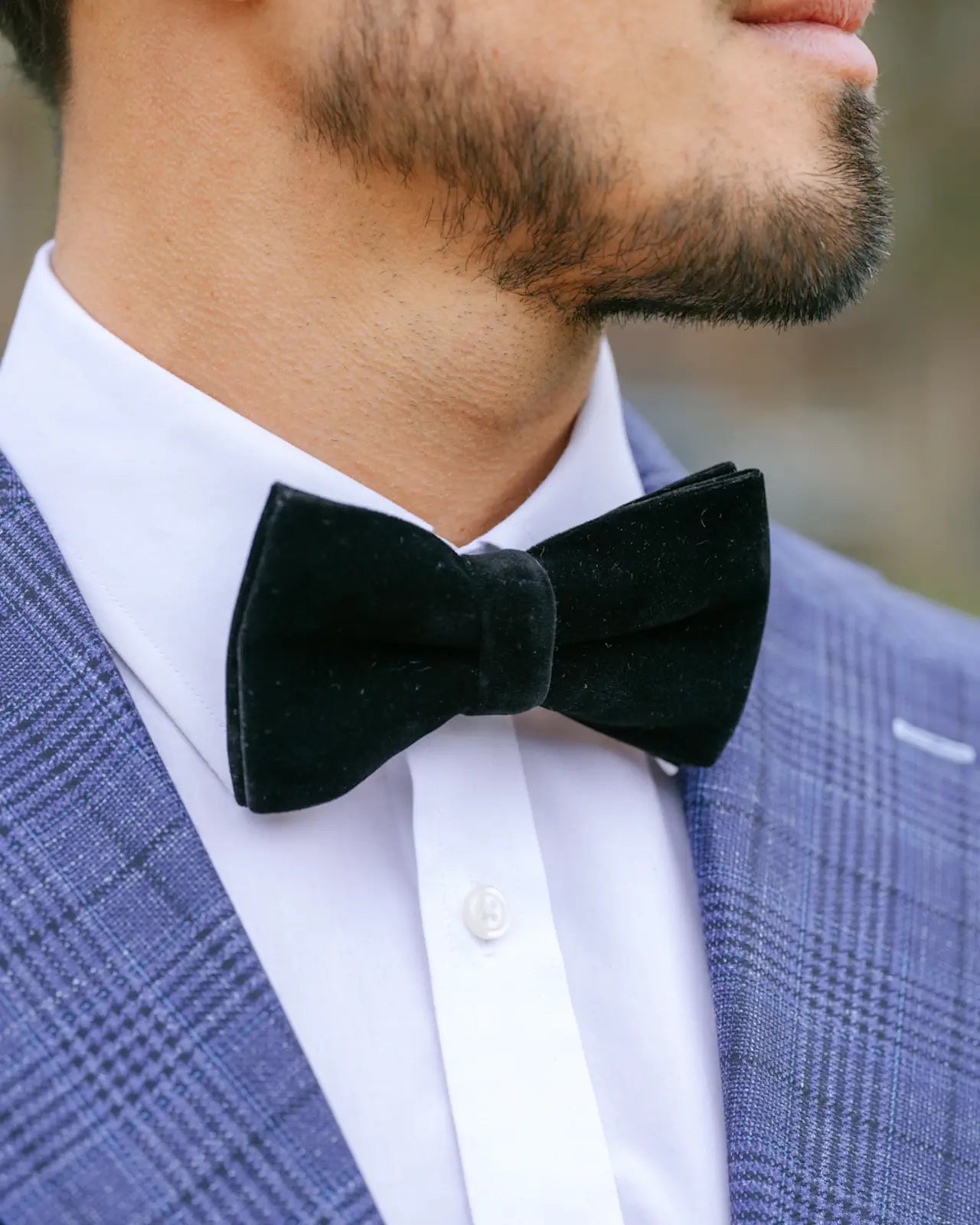 Man wearing a green bow tie with a blue checkered suit jacket.