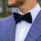 Man wearing a blue checkered suit with a white shirt and navy bow tie.